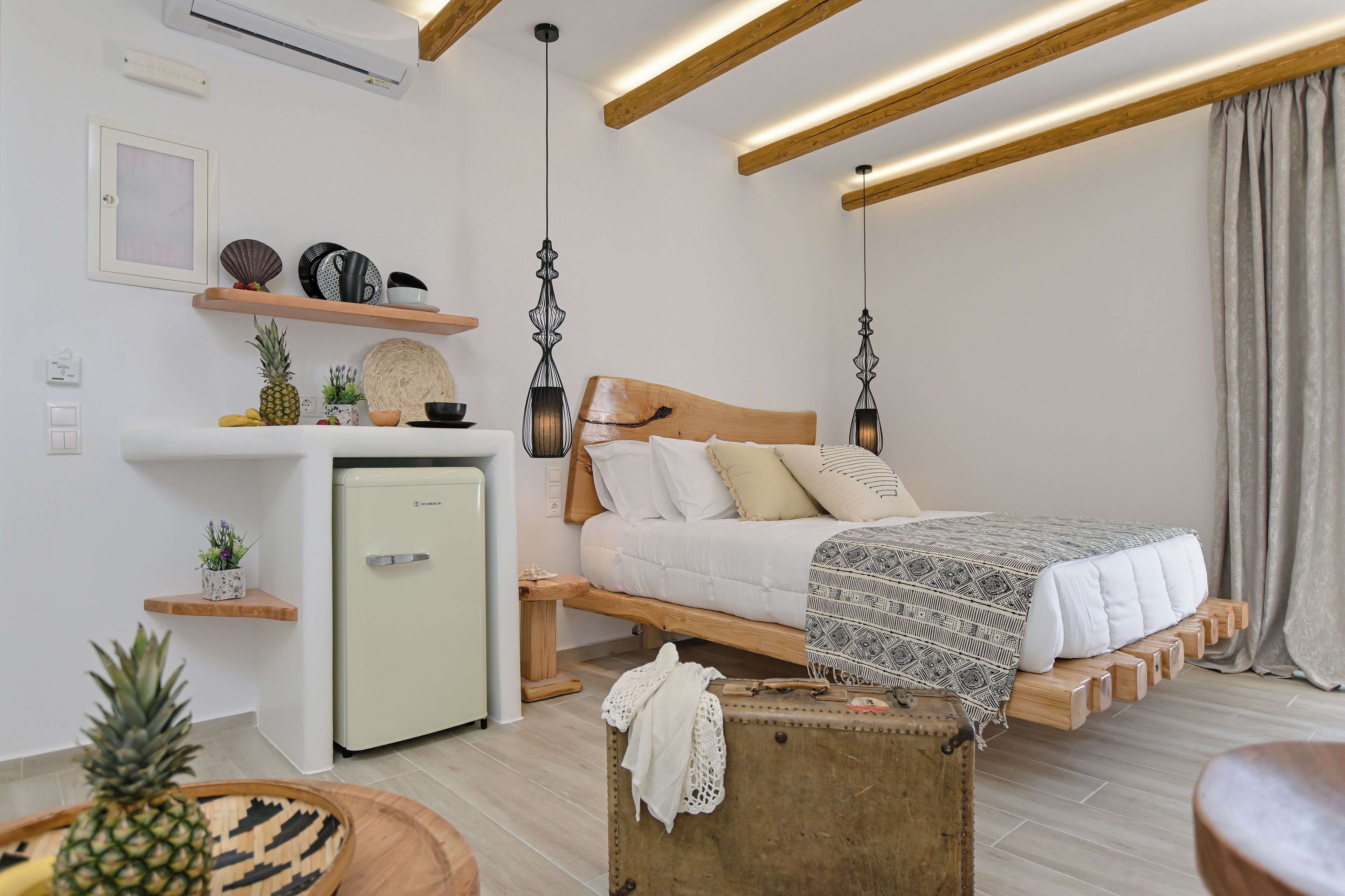 A compact bedroom with a bed, bedside table, and a small refrigerator.