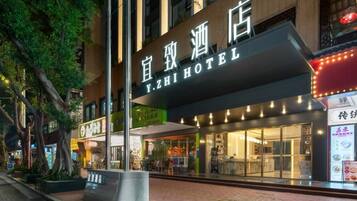 Het uiterlijk van YZHI HOTEL, met een moderne gevel, grote glasramen en een opvallend bord.