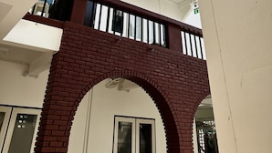 A multi-level building with a brick archway, white walls, and a balcony with railings. - Sleep Owl Chiang Mai  (Chiang Mai)