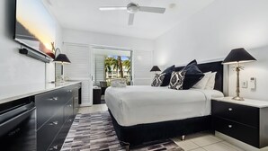 A modern bedroom with a bed, nightstands, a TV, and a ceiling fan.