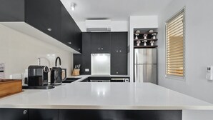 A modern kitchen with black cabinets, a white countertop, stainless steel appliances, and a built-in oven.