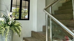Un escalier avec une rampe en verre et un pot de plante placé à côté.