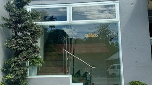 Un bâtiment moderne doté d’une grande baie vitrée, d’un escalier en métal et d’un petit espace jardin agrémenté de galets blancs et de plantes vertes.