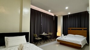 Une chambre d’hôtel avec deux lits, une petite table avec des chaises et une lampe.