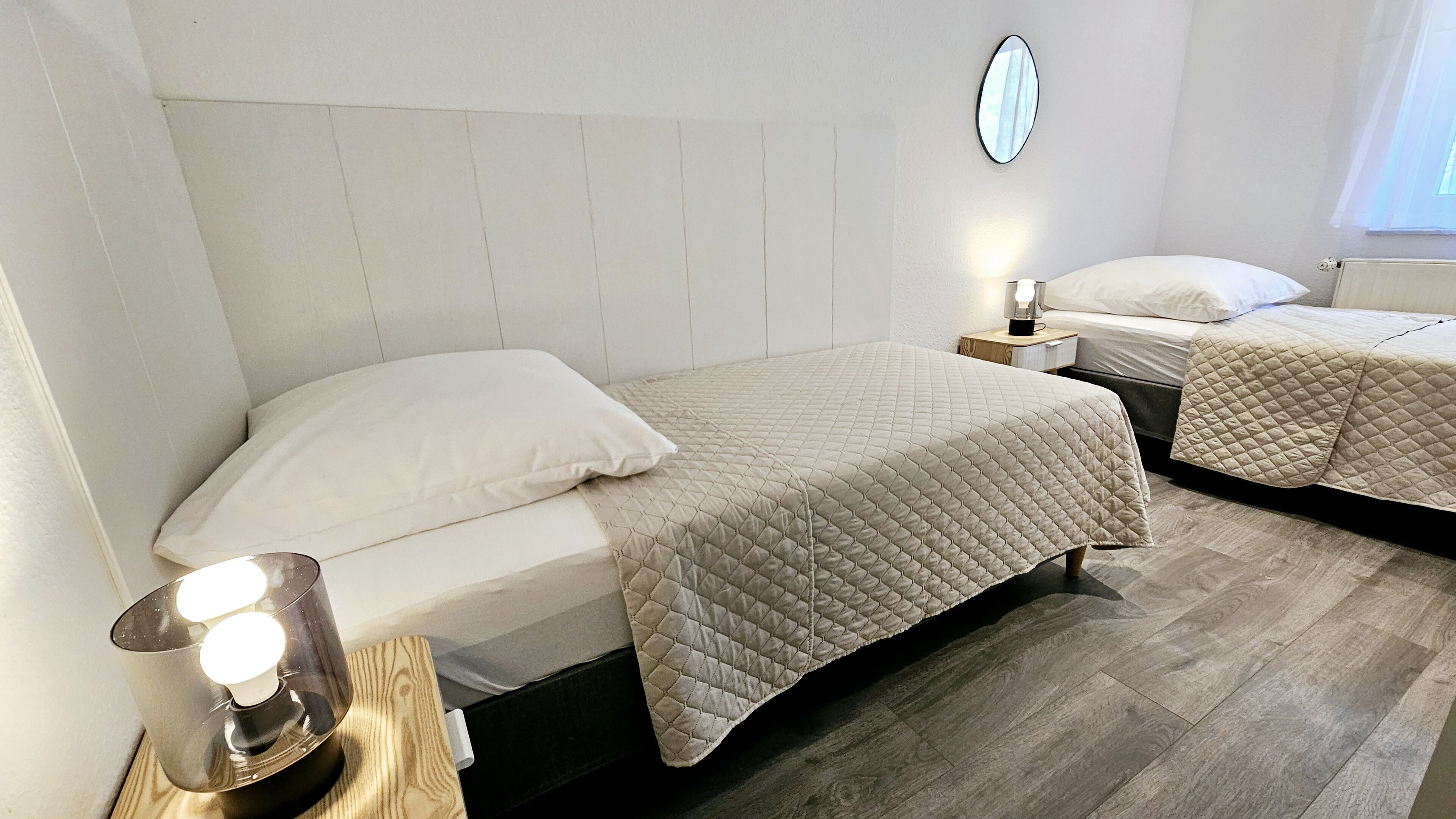 Une chambre d’hôtel avec un lit, une table de chevet, une lampe et un miroir au mur.