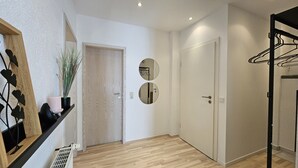 A hallway with wooden flooring, a white door, and a mirror on the wall. - Apartment Marina (Oberzent)