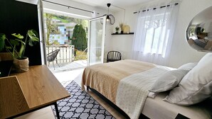 A bedroom with a bed, a desk, a chair, and a balcony with a view of the outside. - Apartment Marina (Oberzent)