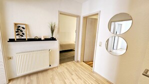 A hallway with a radiator, a shelf with decorative items, and a door leading to a bedroom. - Apartment Marina (Oberzent)