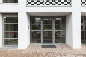 Entrada de um edifício com porta de vidro e portão de segurança de metal.