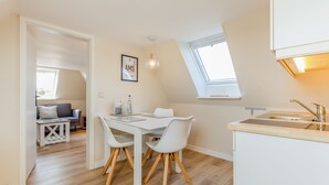 Une cuisine moderne avec un plan de travail blanc, un évier et une fenêtre située au-dessus de l’évier.