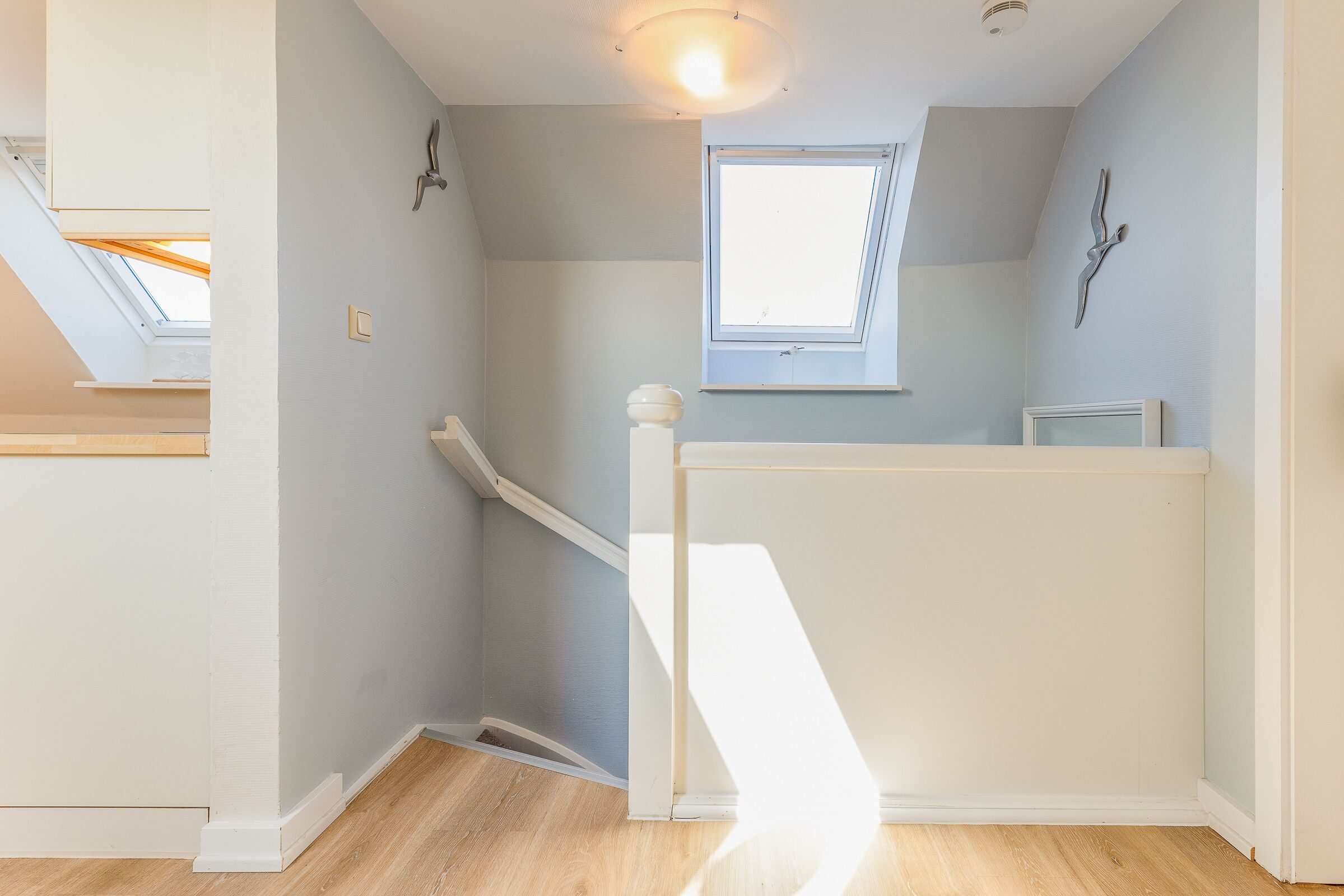 A room with a sloped ceiling, skylight, and a window.