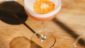 A cocktail glass with a slice of orange on the rim, placed on a wooden surface.
