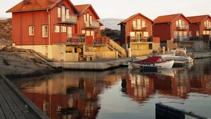 A waterfront property with multiple red wooden houses, a dock, and a boat. - Hotel Strana (Hälleviksstrand)