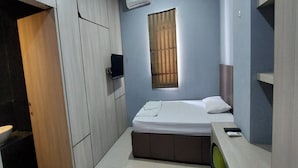 A bedroom with a bed, a desk, a chair, a wardrobe, and a window with blinds. - OYO 93808 Lincoln Dormitory (Curug)