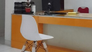 A reception desk with a white chair in front, a computer, and a small plant. - OYO 93808 Lincoln Dormitory (Curug)