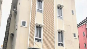 A multi-story building with a beige facade, multiple windows, and a flat roof. - OYO 93808 Lincoln Dormitory (Curug)