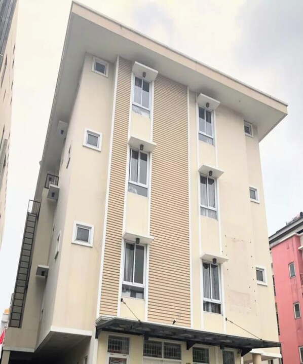 A multi-story building with a beige facade, multiple windows, and a flat roof.