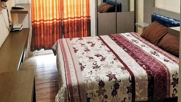 A hotel room with a bed, a wardrobe, an air conditioning unit, and a television. - OYO 93808 Lincoln Dormitory (Curug)