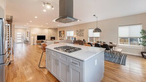 A spacious kitchen with a central island, wooden flooring, and a modern stove. - Spacious Denver Home with Hot tub and Rooftop (Denver)