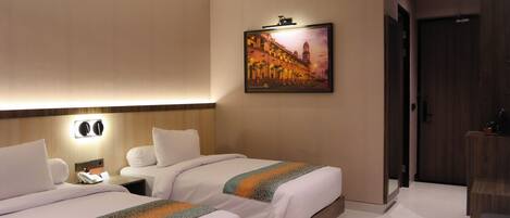A hotel room with two beds, a nightstand, a wall-mounted TV, and a door leading to another room.