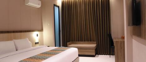 Una habitación de hotel con cama, mesita de noche y televisor en la pared.