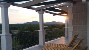 Ein Balkon mit Bergblick, einer Holzbank und einem Geländer.