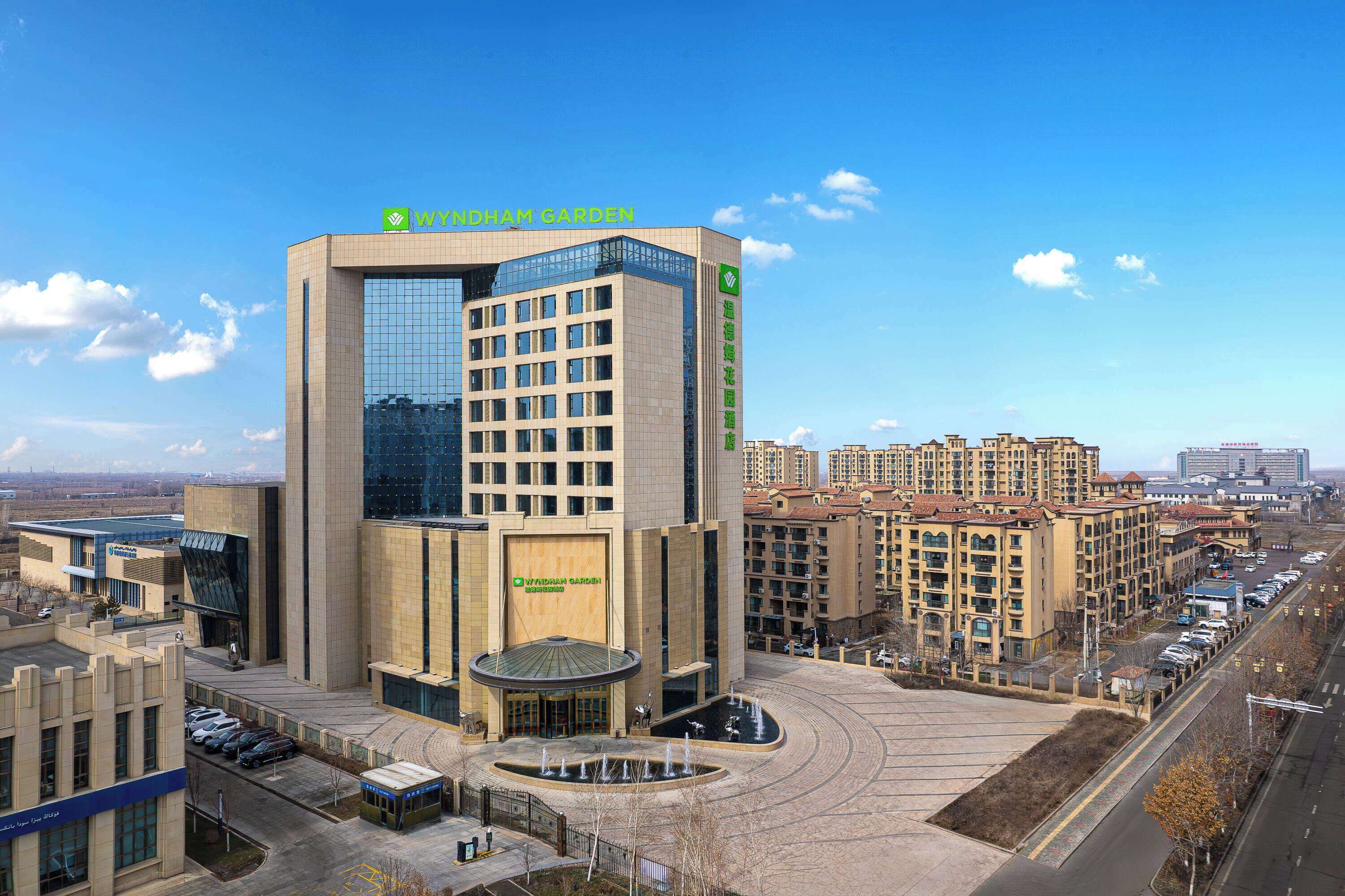 A modern building with a large glass facade and a sign reading "Wyndham Garden."