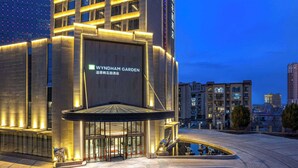 Um hotel moderno com uma entrada imponente, um pátio com piscina e uma placa com a inscrição "WYNDHAM GARDEN".