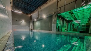 An indoor swimming pool with clear water, tiled walls, and a green-lit ceiling. - Hotel Bizzotel (Gurugram)
