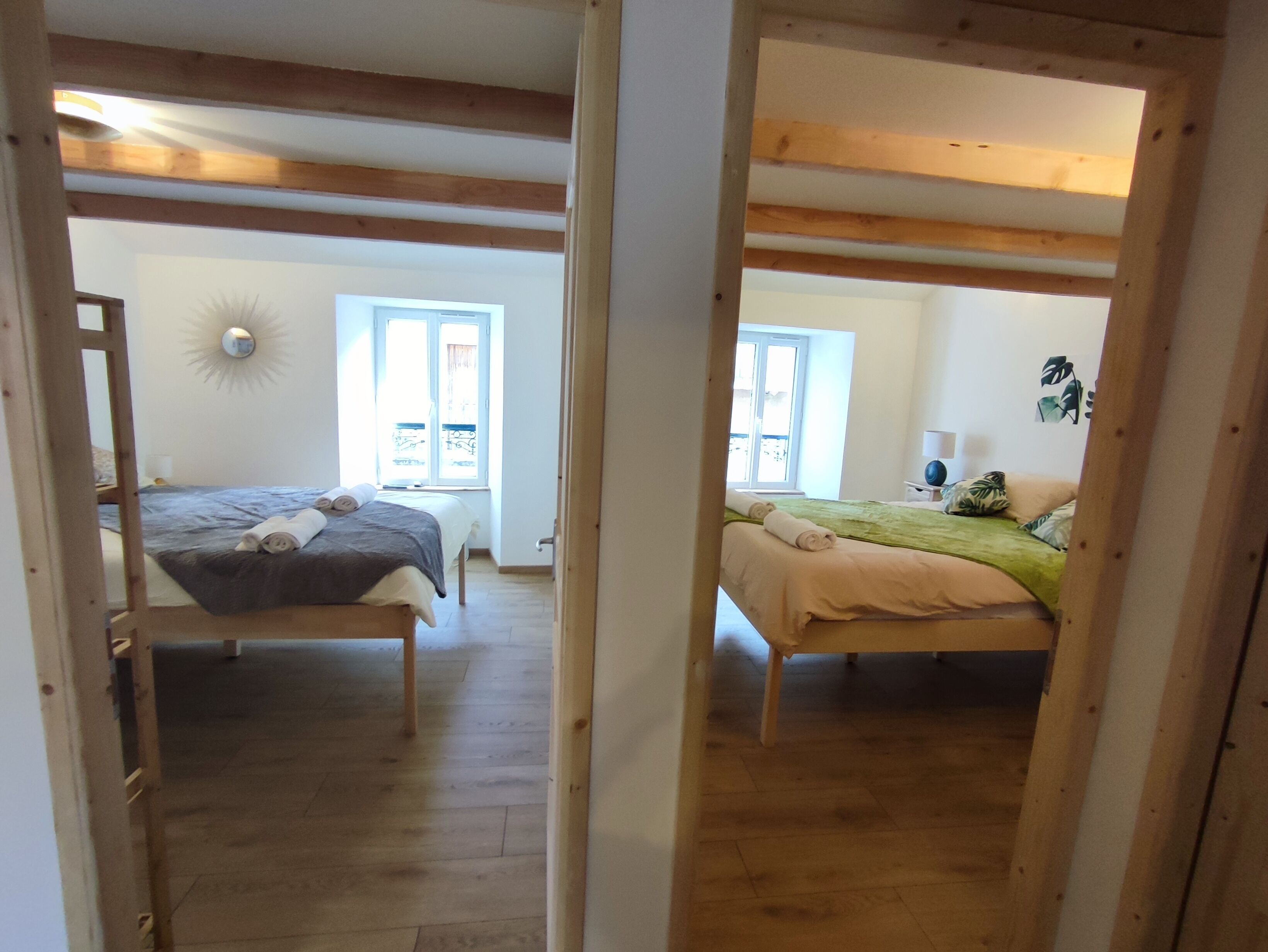 A room with two beds, wooden beams, a sun lamp, and a window.