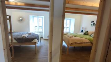 A room with two beds, wooden beams, a sun lamp, and a window.