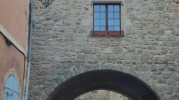 Ein Gebäude aus Stein mit einem großen Bogenportal, einem kleinen Fenster und Blick auf die Straße.