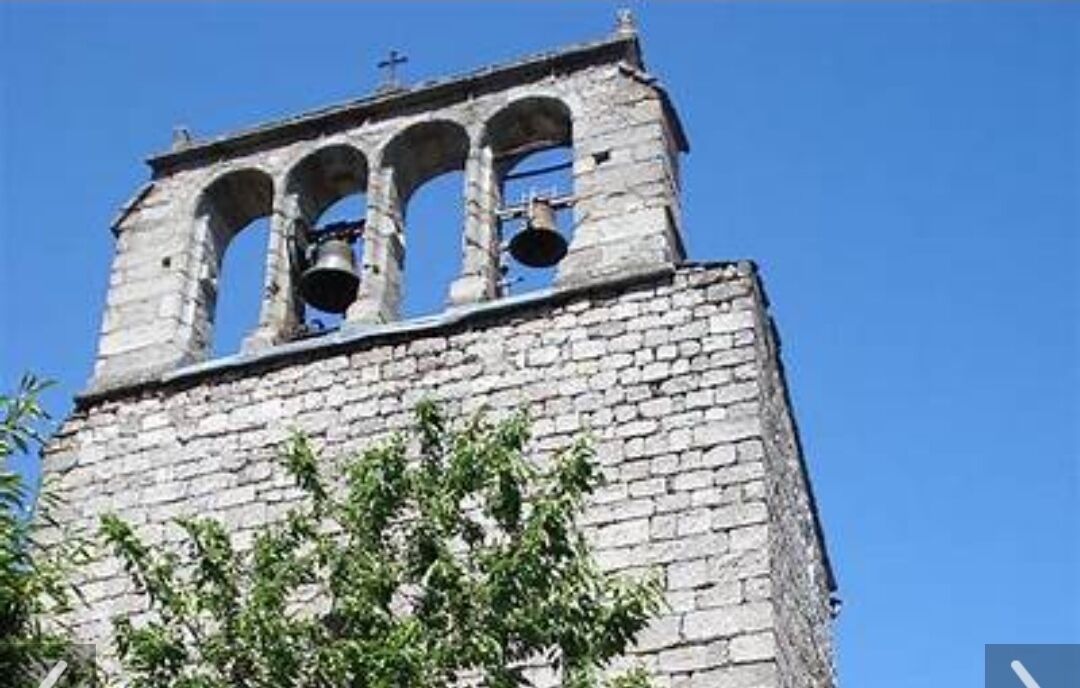 A bell tower with three visible bells and a cross at the top.