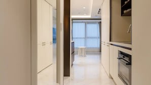 Un pasillo moderno con suelo de mármol que conduce a una habitación con un amplio ventanal y un comedor.