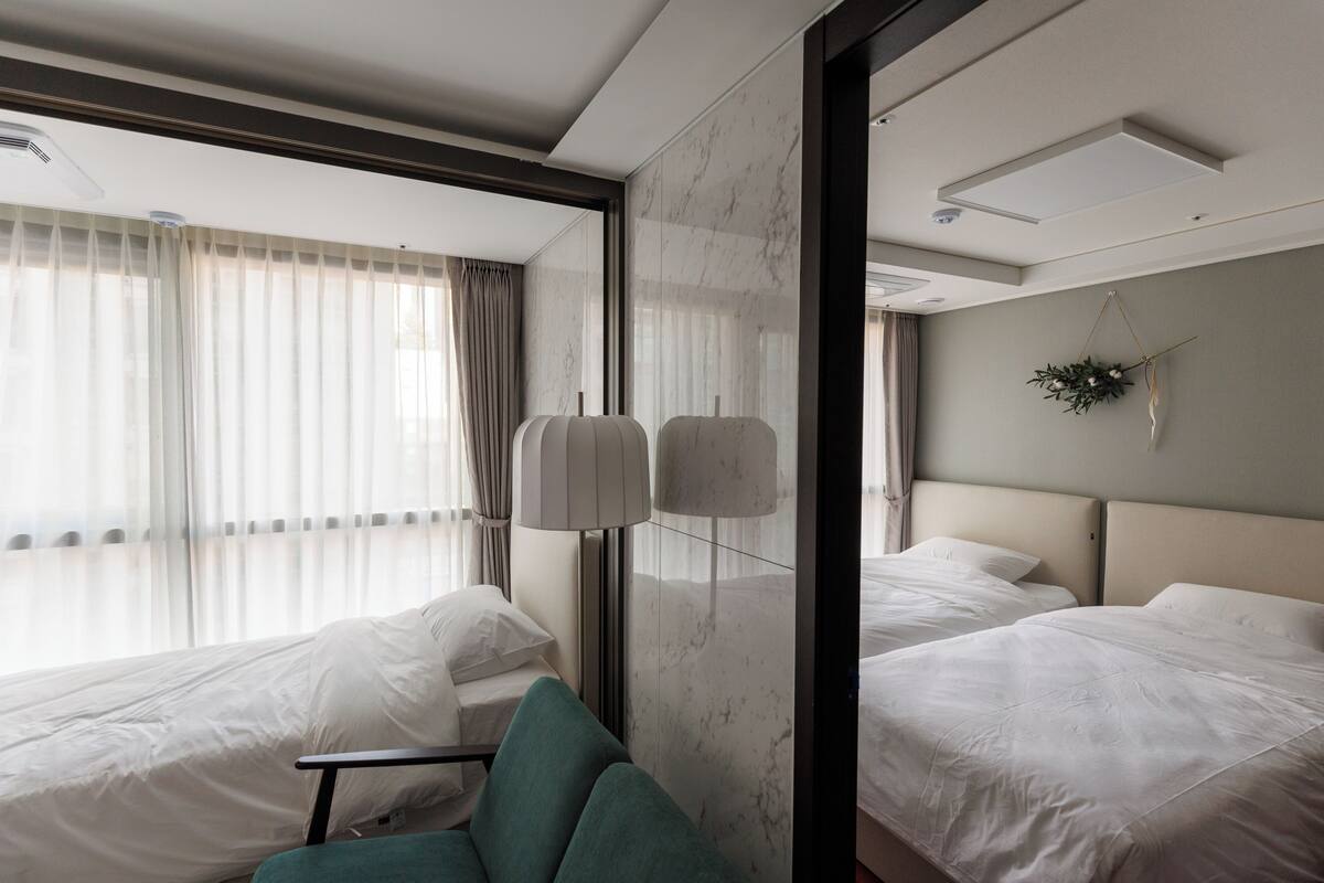 A hotel room with two beds, a seating area, and a large window with curtains.