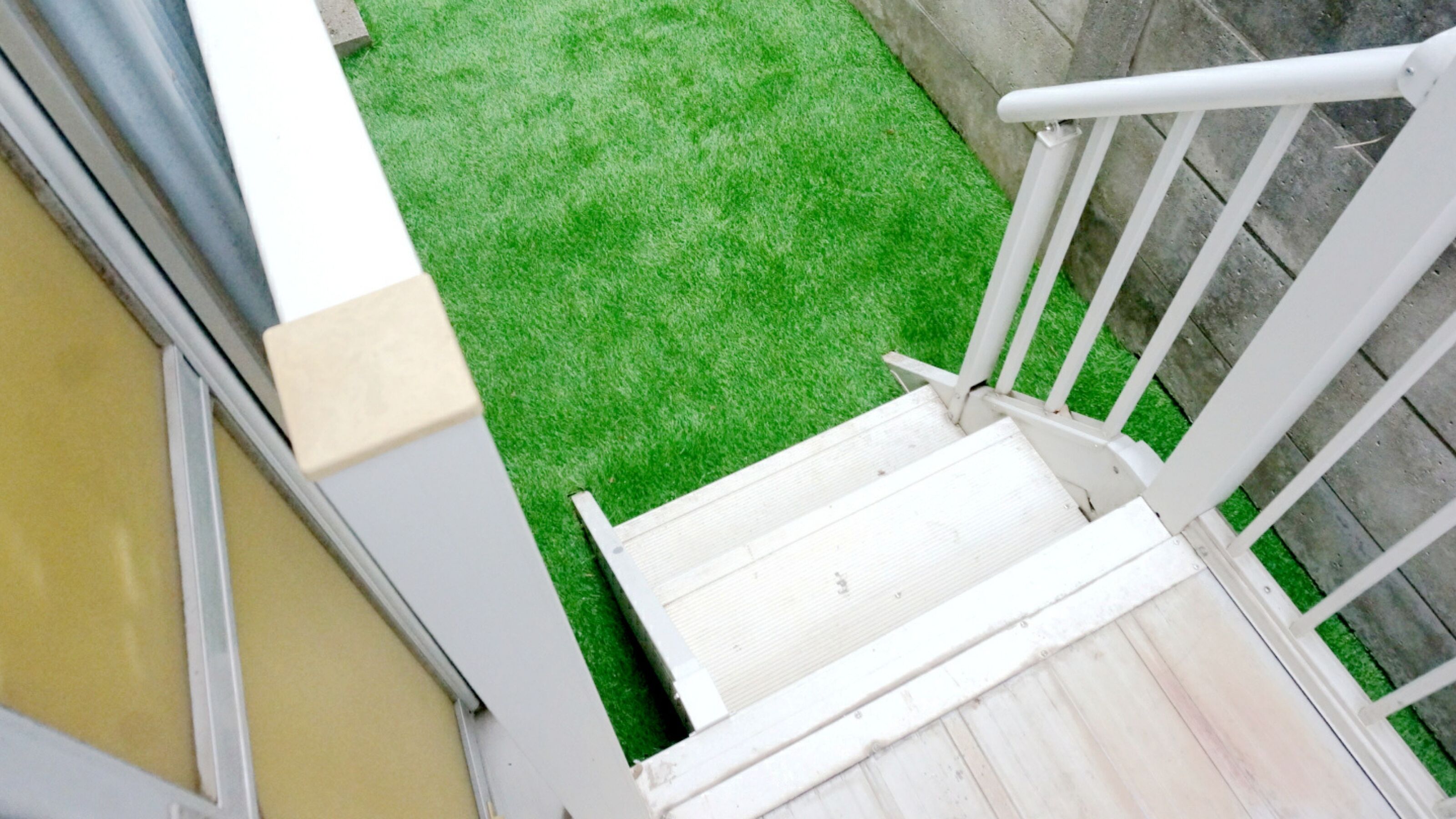 A staircase leading to a green artificial grass area.
