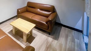 A room with a brown leather sofa, a wooden coffee table, and a light-colored floor. - Tranquil Getaway in the Heart of the City (中野区)
