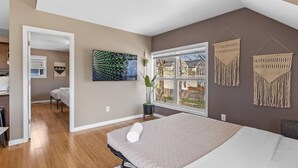 Une chambre à coucher avec un lit, une fenêtre donnant sur un beau paysage, des décorations murales en macramé et un tableau.