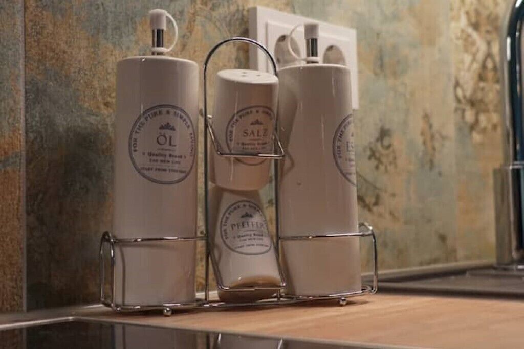 Trois flacons de produits de toilette dans un présentoir en métal, posés sur un comptoir.