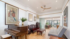A spacious living room with a grand piano, a sofa, and a coffee table. - Beautiful 6bed house near Kensinghton Park (London)