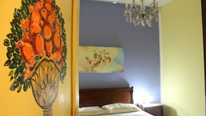 A bedroom with a bed, a chandelier, and a painting on the wall.