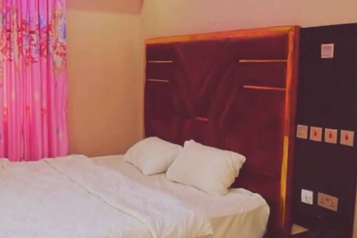 A bedroom with a bed, a wooden headboard, and a curtain.