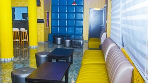 Un intérieur moderne avec des sièges jaunes et bleus, un coin bar et une grande fenêtre.