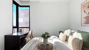 A bedroom with a bed, a desk, a window, and a wall-mounted picture.