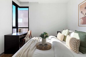 Ein Schlafzimmer mit Bett, Schreibtisch, Fenster und einem Wandbild.