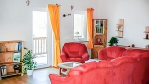 Una sala de estar con un sofá rojo, un armario de madera y una planta en maceta.
