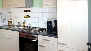 Una cocina con armarios blancos, estufa y cafetera.