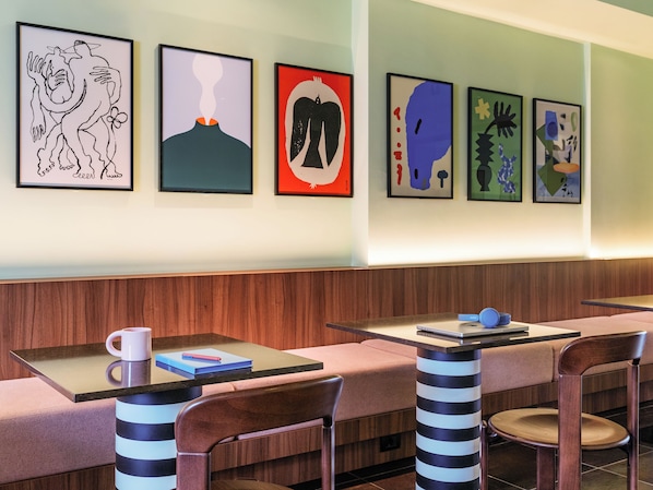 A modern restaurant with wooden paneling, striped chairs, and abstract art on the wall.