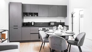 Una cocina moderna con armarios grises, un microondas y un comedor con una mesa para dos.