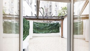 Un interior moderno con un vidrio que da a un balcón con pared verde y suelo de baldosas.